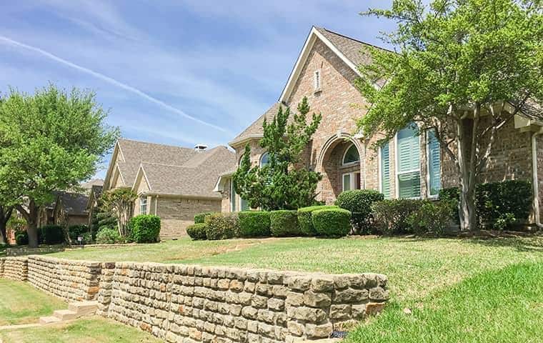 A house with a stone wall in front of it, located in Arlington, TX.