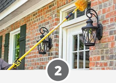 A man cleaning a window with a yellow broom in his home for efficient pest control.