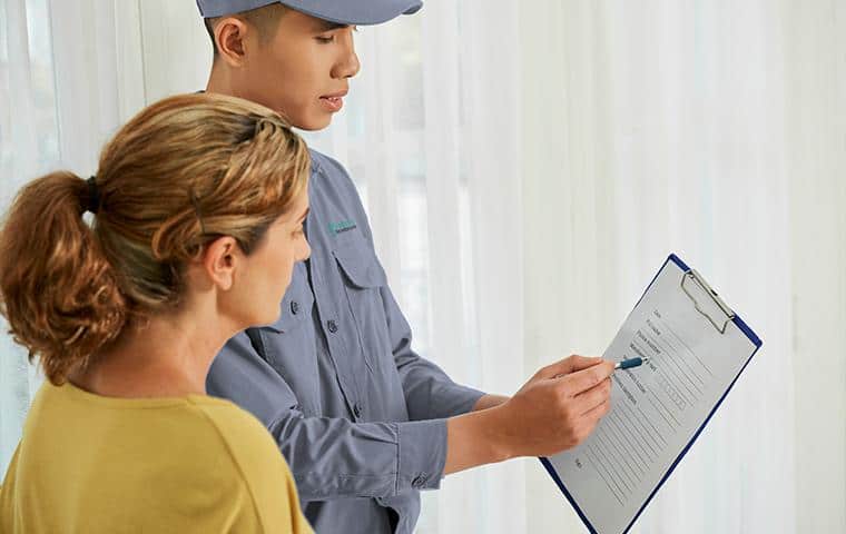 A man holding a clipboard while a woman is looking at it, working on Ornamental Care in Tarrant County, Inc.