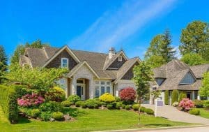 A beautiful home with an abundance of landscaping in the front yard, featured on a blog discussing the benefits of deep root feeding for Arlington trees.